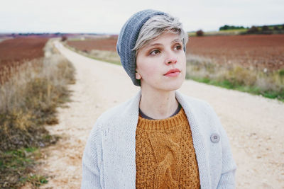 Close-up of woman wearing knit hat while standing on dirt road