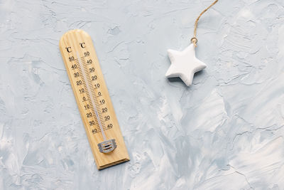 Thermometer shows low temperature and christmas star decoration on white and blue background. winter