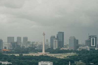 Buildings in city against cloudy sky