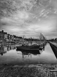 Boats moored at harbor against sky in city