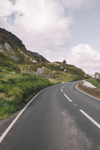 Empty road by mountain against sky