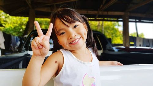 Portrait of smiling girl showing peace sign