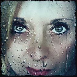 Portrait of woman with raindrops on window