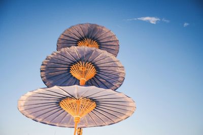 Low angle view of traditional umbrellas against blue sky