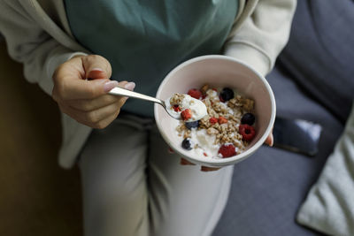 Woman holding bowl of yogurt and muesli