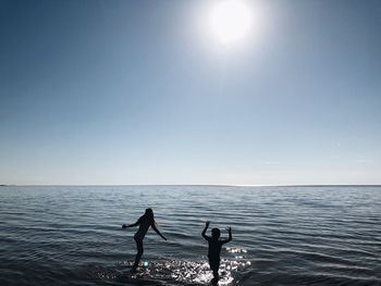 Rear view of girl with brother in sea