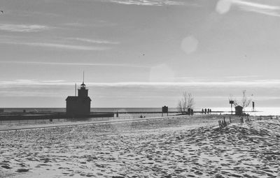 Lighthouse on beach against sky