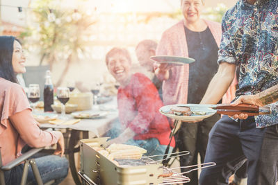 Cropped hand serving food to friend at backyard