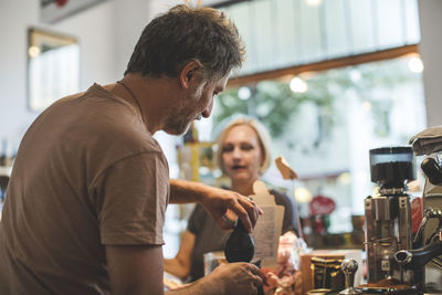 Male and female employees working at checkout counter in deli