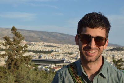 Portrait of young man with sunglasses standing on mountain