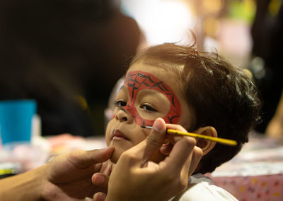 Close-up person applying face paint on boy