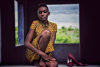 Portrait of young woman sitting on window
