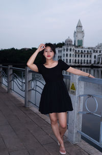 Portrait of young woman standing against building