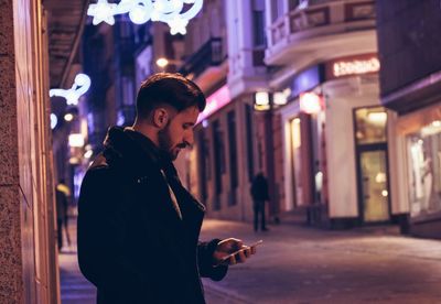 Man looking at phone in city during night