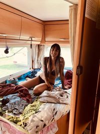 Portrait of woman in bikini sitting on bed in caravan