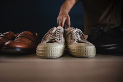 Hands holding white shoes on floor