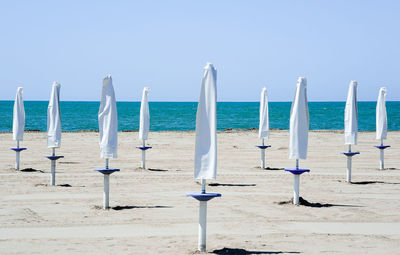 Wooden posts on beach against clear blue sky