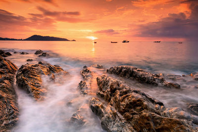 Beautiful motion sea wave through natural rock at sunset with twilight sky in kalim beach, phuket, 