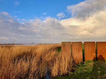 Wooden fence on field against sky