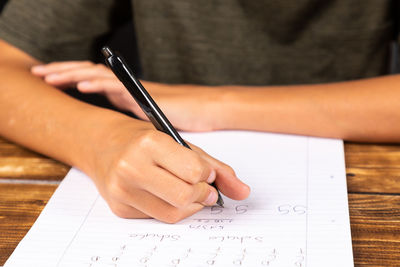 Midsection of girl writing over paper on table