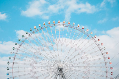 Low angle view of ferris wheel against cloudy sky