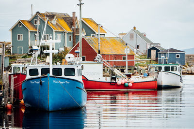 Boats moored in canal by buildings against sky