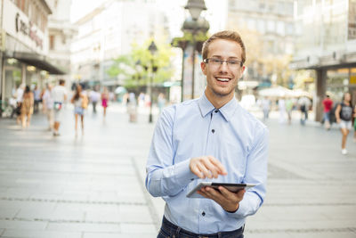 Portrait of young man standing on city street