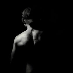 Rear view of young woman standing against black background