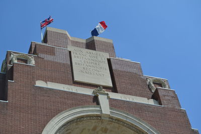 Low angle view of flag on building against clear blue sky