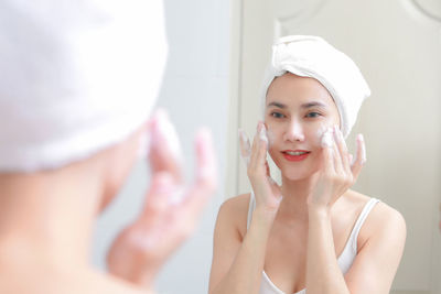 Woman applying face wash in bathroom