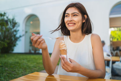 Portrait of a smiling young woman sitting on table