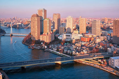 Wide angle aerial panoramic view of sumida river with skyscrapers, bridges and boats on sunset