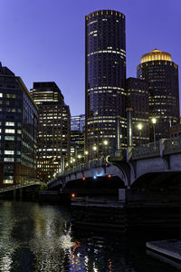 Illuminated bridge over river in city at night