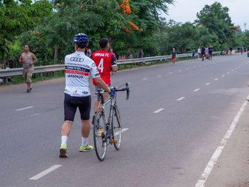 Rear view of people riding bicycle on road