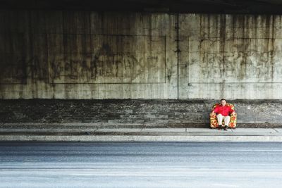 Man sitting on sofa at sidewalk