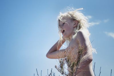 Portrait of young woman standing against sky