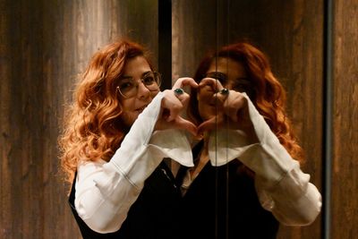 Portrait of woman standing with reflection in mirror