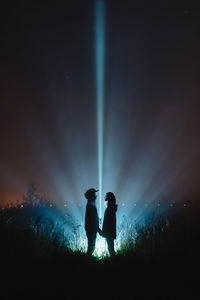 Couple standing on field against sky at night