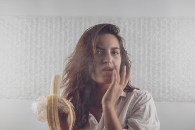 Portrait of woman eating banana at home