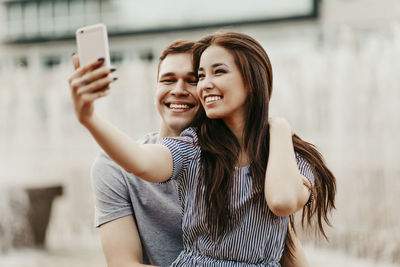 Happy couple talking selfie in city during sunset