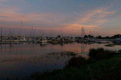 Boats in harbor during sunset with colorful sky reflecting in water