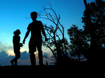 Silhouette people standing against blue sky