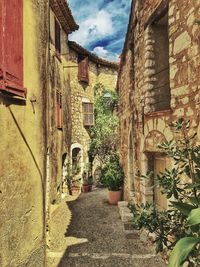 Alley amidst houses against sky