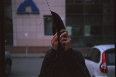 Portrait of woman holding glass window