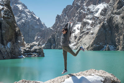 Full length of woman standing on rock by lake