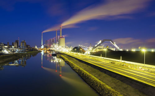 Illuminated bridge over river against sky at night