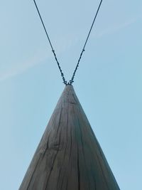 Low angle view of wooden pole with cables against sky