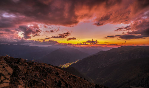 Scenic view of mountains against dramatic sky during sunset