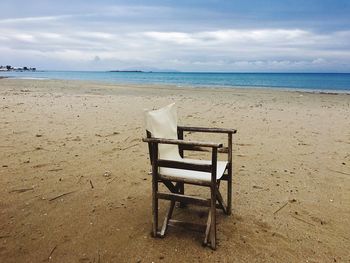 Chair on beach against sky