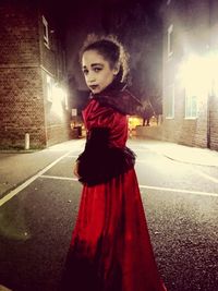 Portrait of woman standing on road at night